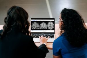 Two women examining brain scan images on a laptop